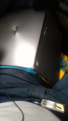 Liquid Spill On A Laptop: What To Do? Full Guide To Recover Your Laptop! : Holding a laptop upside down on leg during a flight with a towel pressed against keyboard to mop up liquid Aperol Spritz spilled on laptop